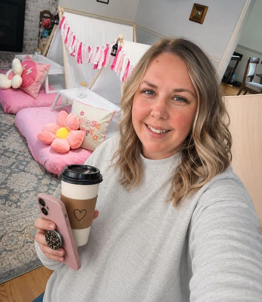 Crystal Hickman, owner of Magnolia Slumber Rental, smiling with a coffee in front of one of her pink teepee setups